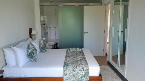 a bedroom with a white bed and a bathroom at ISLA HOLIDAY HOME in Anse Royale