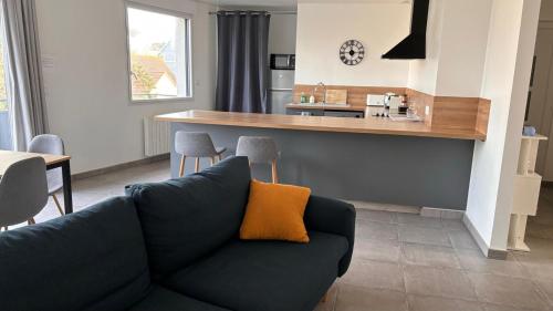 a living room with a couch and a kitchen at Bel appartement à 200m de la plage in Barneville-Carteret