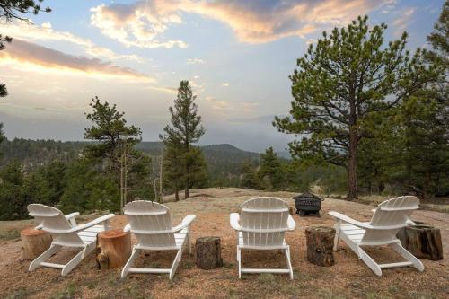 a group of white chairs sitting on top of a field at 5 Acres! Modern Cabin w/ Pikes Peak View in Florissant