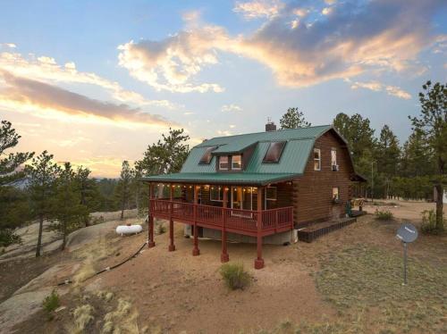 a house with a green roof on top of a field at 5 Acres! Modern Cabin w/ Pikes Peak View in Florissant