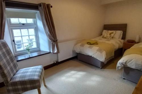 a bedroom with two beds and a window at Peak District - 1 Harrow Cottage - Great Longstone in Great Longstone