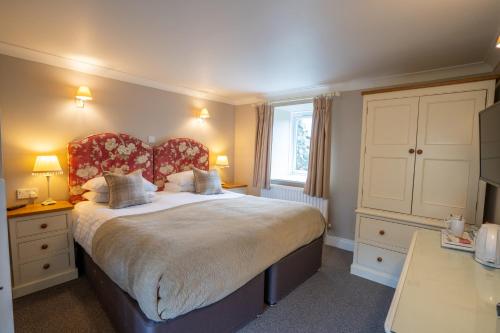 a bedroom with a large bed with a red headboard at The Pheasant Inn in Falstone