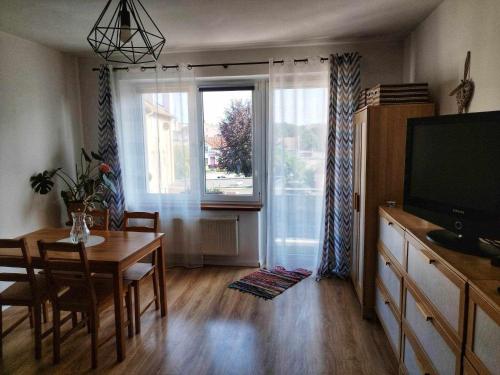 a living room with a dining room table and a television at Apartament Kajki in Mrągowo