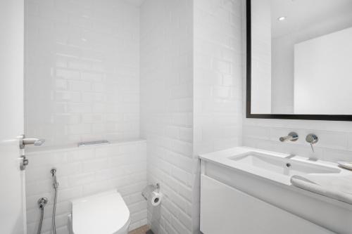 ein weißes Bad mit einem Waschbecken und einem WC in der Unterkunft Silkhaus Luxurious 1BDR with Beach Access and City View in Abu Dhabi