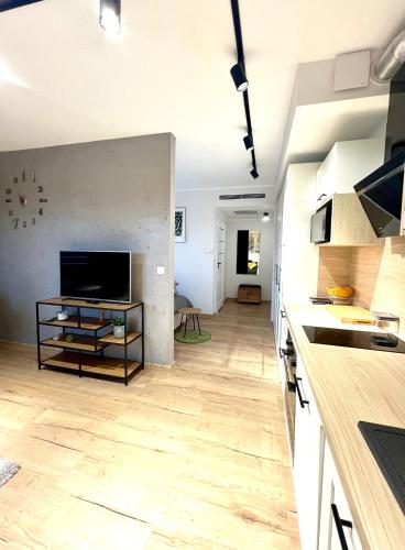 a kitchen with white cabinets and a wooden floor at Piękny Apartament Blisko Morza - Sarbinowo in Sarbinowo