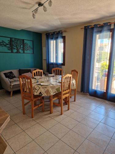 a dining room with a table and chairs and a couch at Villa 6p piscine spa privatif wifi proche des plages in Le Barcarès