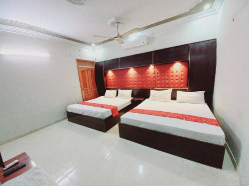 1 dormitorio con 2 camas con luces rojas en el cabecero en Rose Palace Guest House en Karachi