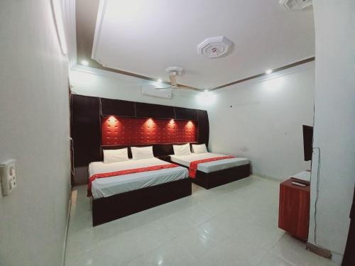 1 dormitorio con 2 camas con luces rojas. en Rose Palace Guest House en Karachi