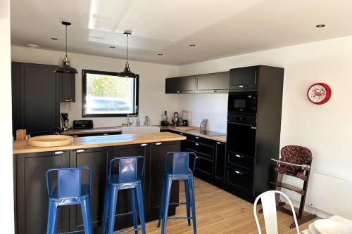 una cocina con armarios negros y taburetes azules en Villa familiale, commerces à pied, mer à 5 min en Penvénan