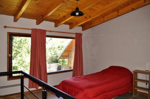 a bedroom with a red bed and a window at Cabaña en Villa Los Coihues in San Carlos de Bariloche