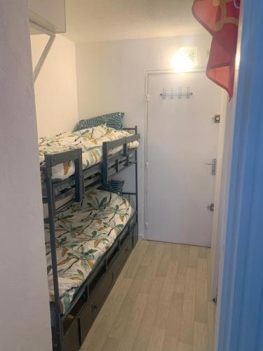 Cette petite chambre comprend 2 lits superposés et une porte. dans l'établissement Joli studio proche plage du Môle, au Cap d'Agde