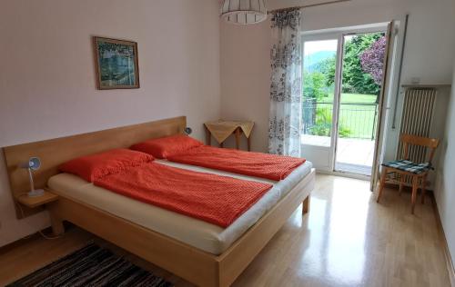 Schlafzimmer mit einem Bett mit roter Bettwäsche und einem Fenster in der Unterkunft Haus Klavenz in Kaltern