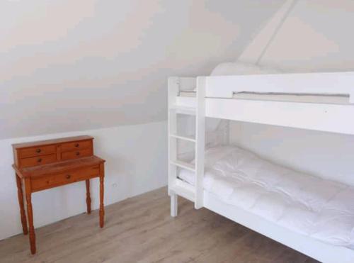 ein Schlafzimmer mit einem weißen Etagenbett und einem Holztisch in der Unterkunft Maison au calme in Erquy