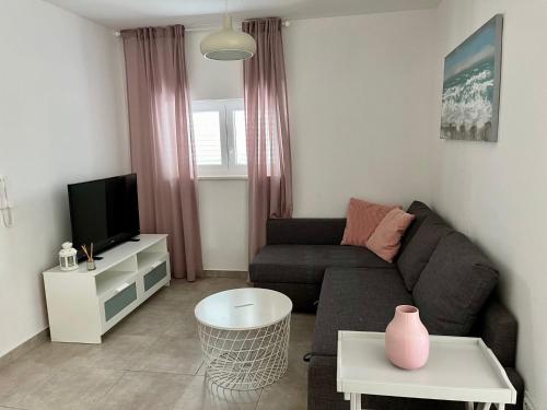 ein Wohnzimmer mit einem Sofa und einem TV in der Unterkunft Olive place 2 in Tisno