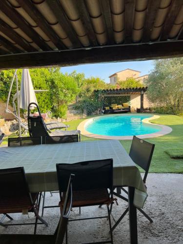 uma mesa e cadeiras num quintal com piscina em Villa avec piscine au soleil de la côte d’azur em Mouans-Sartoux