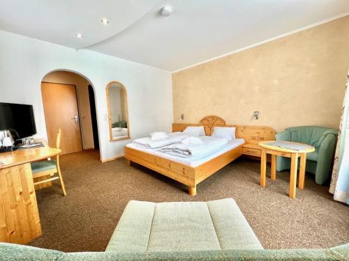 1 dormitorio con cama, sofá y TV en Hotel Garni Burger, en Sankt Jakob in Defereggen