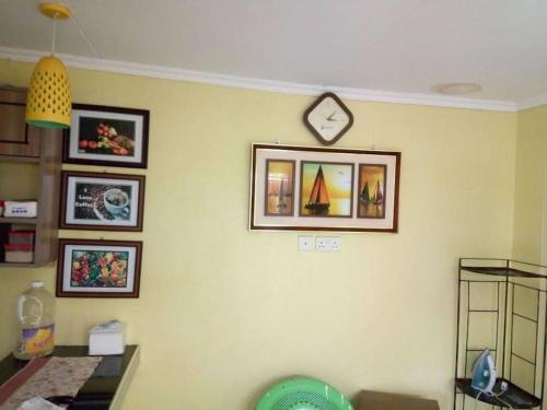 een kamer met een klok aan een muur met foto's bij Stay with Daktari Homes in Homa Bay