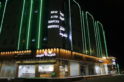 una tienda frente a un edificio por la noche en Bahget Eljouf Furnished Apartment en Aţ Ţuwayr