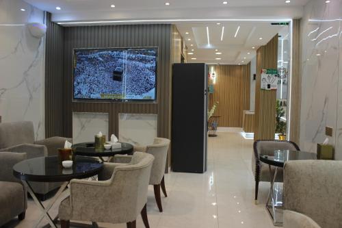 un vestíbulo con mesas y sillas y TV en la pared en Bahget Eljouf Furnished Apartment en Aţ Ţuwayr