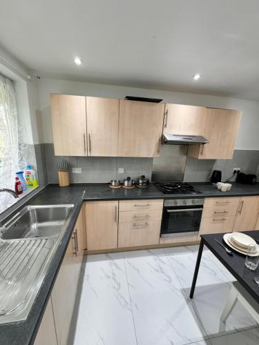 a large kitchen with wooden cabinets and a sink at Luxury rooms in Bow in London