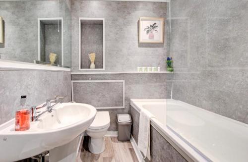 uma casa de banho com um lavatório, uma banheira e um WC. em Elegant 1 Bedroom Flat em Brentwood