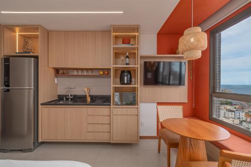 - une cuisine avec des murs orange, une table et un réfrigérateur dans l'établissement Studio com vista do Mar em Salvador/Ba, à Salvador