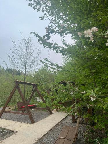 a wooden swing set in a garden with trees at Симфонія біля річки Чан in Skole
