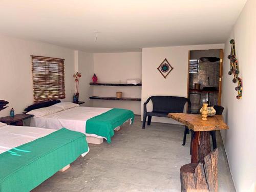 a bedroom with two beds and a table and a chair at La Triada in Ríohacha