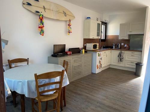 une cuisine avec une table et une planche de surf accrochée au mur dans l'établissement Studio avec jardinet Mimizan plage, à Mimizan
