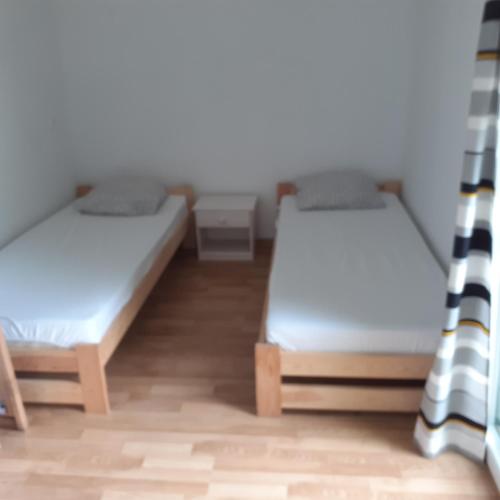 two beds in a small room with wooden floors at domek na skarpie in Ruciane-Nida