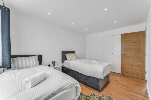 two beds in a bedroom with white walls and wooden floors at Relaxed Home in Eltham