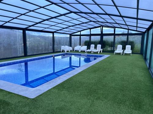a house with a swimming pool with chairs and a roof at Casa Rural Vivienda Vacacional L´Curuxa Complejo CaleaCabo in Biescas