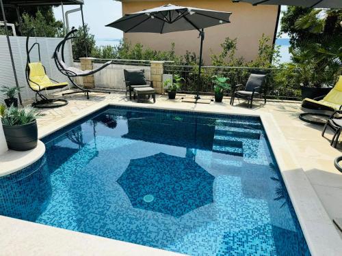 a swimming pool with chairs and an umbrella at Villa Sirenis in Trogir