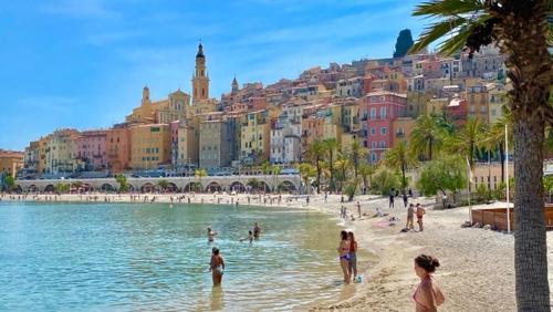 a group of people on a beach in front of a city at MENTON # MONACO - F1 GP - 4 PERSONS - SEA VIEW - NEW - PARKING - CLIM - PREMIUM - BEACH and SUN in Menton