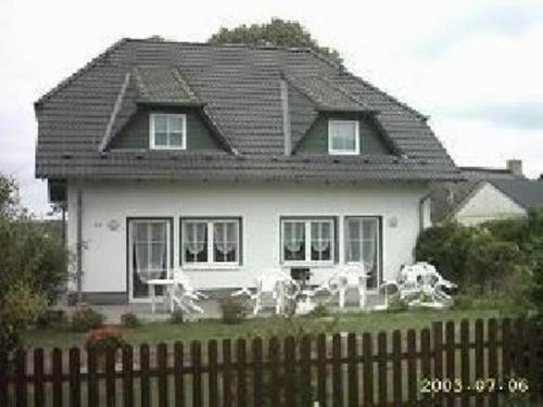 une maison blanche avec un toit noir et des chaises blanches dans l'établissement Ferienwohnung für 2 Personen ca 32 qm in Pantow, Ostseeküste Deutschland Rügen, à Pantow