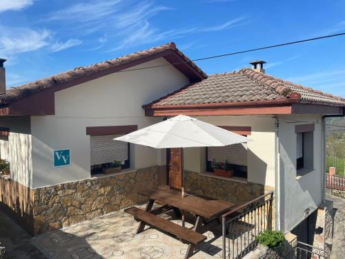 a house with a wooden table and an umbrella at La Ventana de Picos in Onís