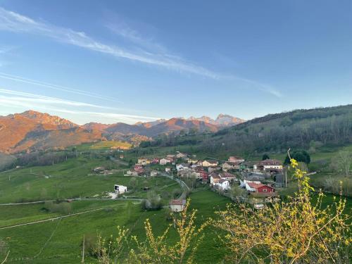 a town in a green field with mountains in the background at La Ventana de Picos in Onís