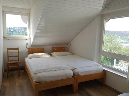 Cama en habitación con 2 ventanas y silla en Ferienwohnung Wiedmann, en Tübingen