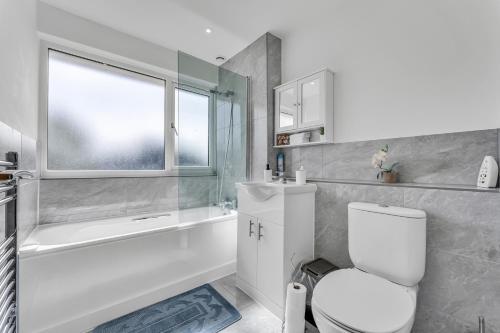 a bathroom with a toilet and a tub and a window at Relaxed Home in Eltham