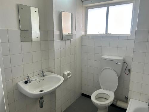 a white bathroom with a toilet and a sink at Fine living apartment in Vredendal