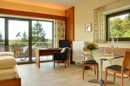 a living room with a table and a dining room at Allgäu-Hotel-Elbsee in Aitrang