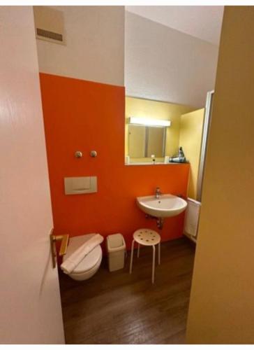 an orange bathroom with a toilet and a sink at Apartment im Hotel Rottalblick in Oberham