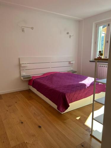 um quarto com uma cama com lençóis roxos e uma janela em Casa Elogi em Buti
