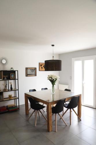 une table à manger avec des chaises et un vase de fleurs dans l'établissement Maison - 3 chambres - Jardin, à Huisseau-sur-Cosson