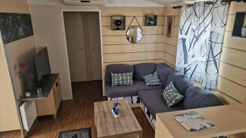 sala de estar con sofá azul y mesa en Mobil-home de vacances, en Le Bosc