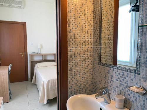 ein Bad mit einem Waschbecken und ein Bett in einem Zimmer in der Unterkunft Hotel Majestic in Senigallia