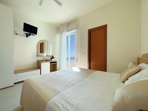 ein weißes Schlafzimmer mit einem großen Bett und einem Spiegel in der Unterkunft Hotel Majestic in Senigallia