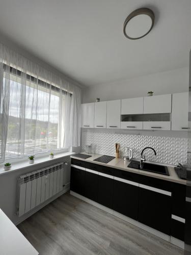 cocina con armarios blancos, fregadero y ventana en 4 kąty na granicy z Sopotem en Gdansk