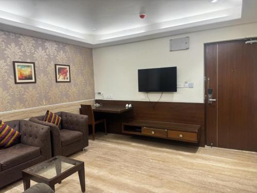 a living room with a couch and a flat screen tv at Hotel Luxury Holiday - Banjara hills prime location in Hyderabad