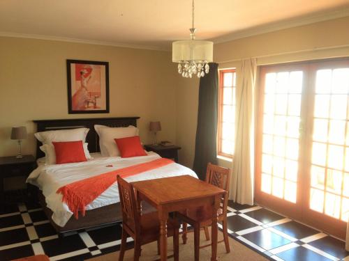 a bedroom with a bed with red pillows and a table at Helderberg Guesthouse in Gordonʼs Bay